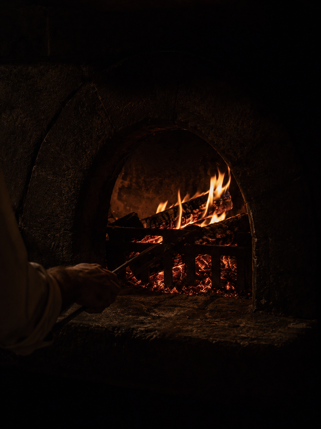 Wood-fired hearth glowing through an arched stone opening